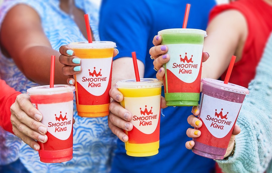 group of people holding up Smoothie King smoothies in rainbow of colors