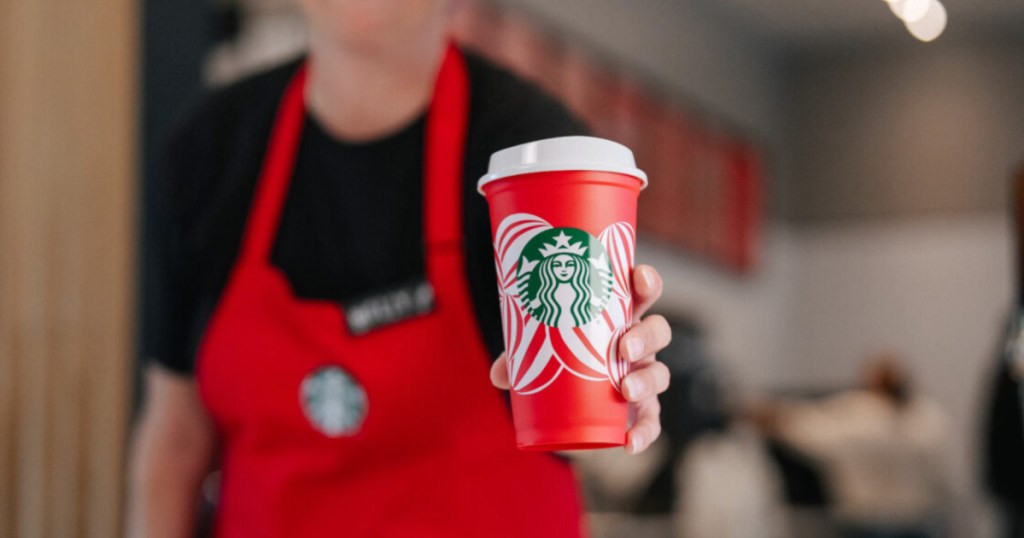 starbucks employee handing out a Starbucks red cup