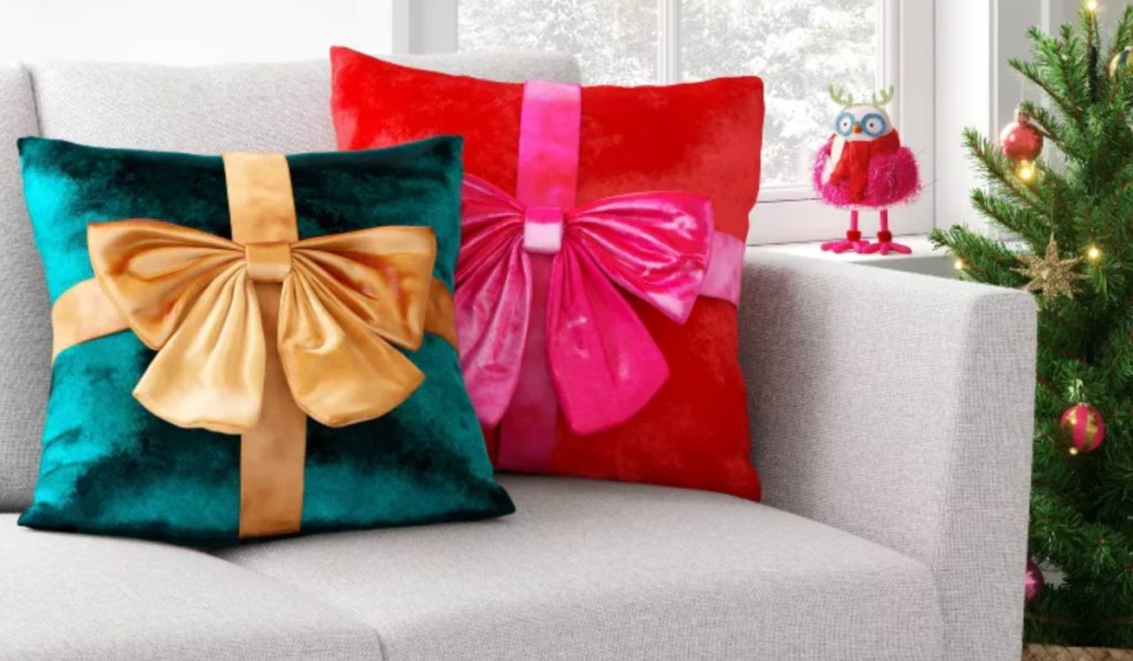 Red and green bow throw pillows on couch next to Christmas tree
