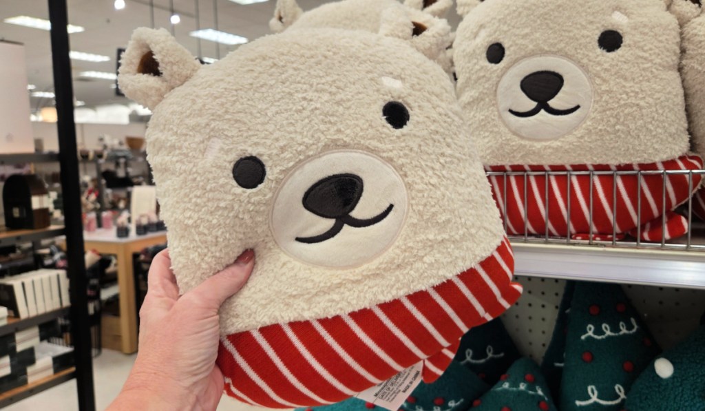 Woman holding white holiday bear pillow inside target store