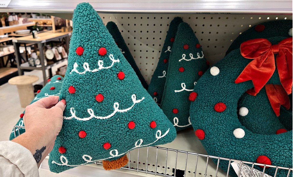 Person holding up Christmas tree pillow inside target store