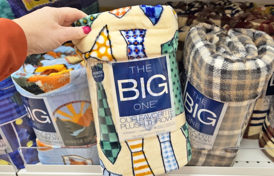 hand grabbing a neck tie print throw blanket from store shelf