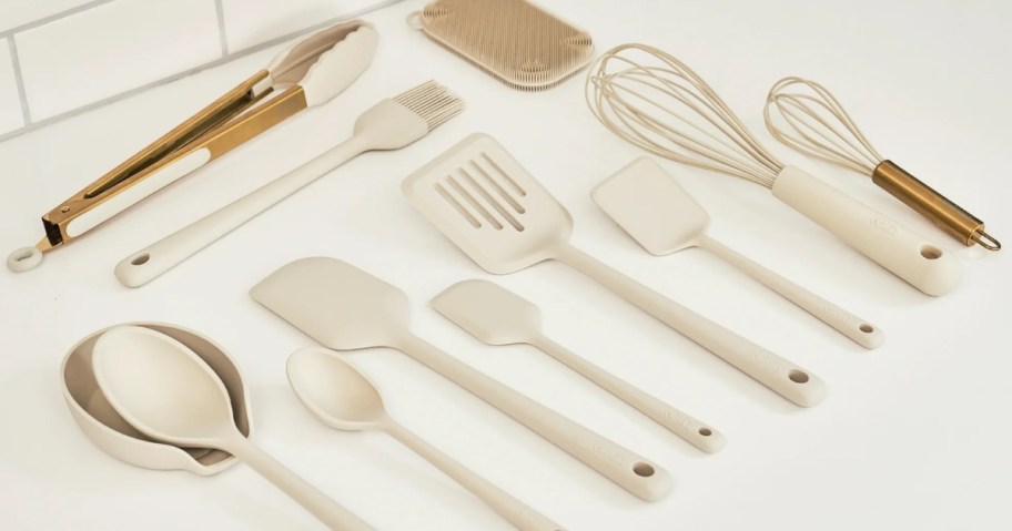 a set of cream and gold color cooking utensils on a kitchen counter