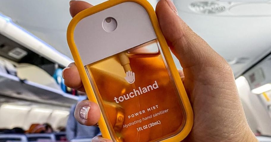 Hand holding a Touchland Hand Sanitizer Spray