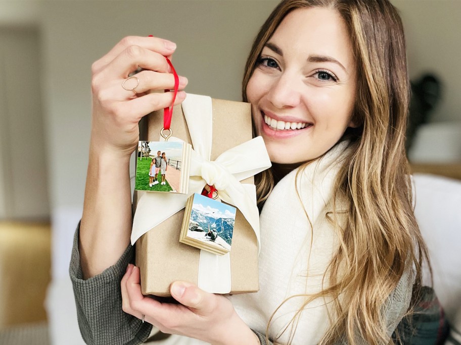 woman holding up wood photo ornaments and wrapped present