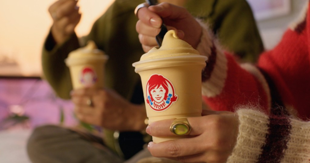 person holding Wendy's Caramel Frosty and eating it with a spoon