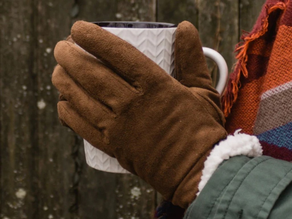 woman wearing brown gloves and holding hot drink