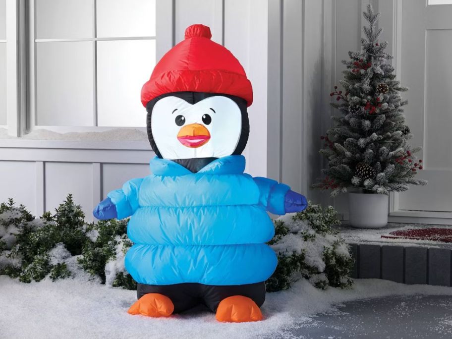 Inflatable Penguin in Puffer Jacket in front of a house