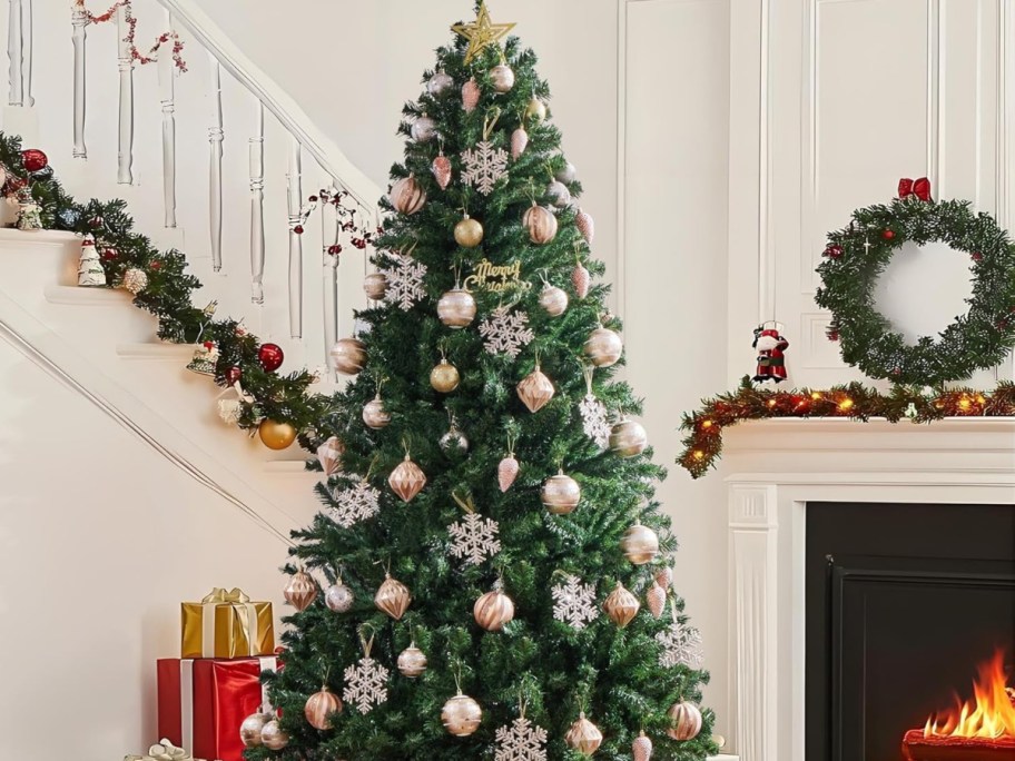 Yaheetech 6ft Premium Spruce Hinged Artificial Christmas Tree displayed in the living room next to a fireplace