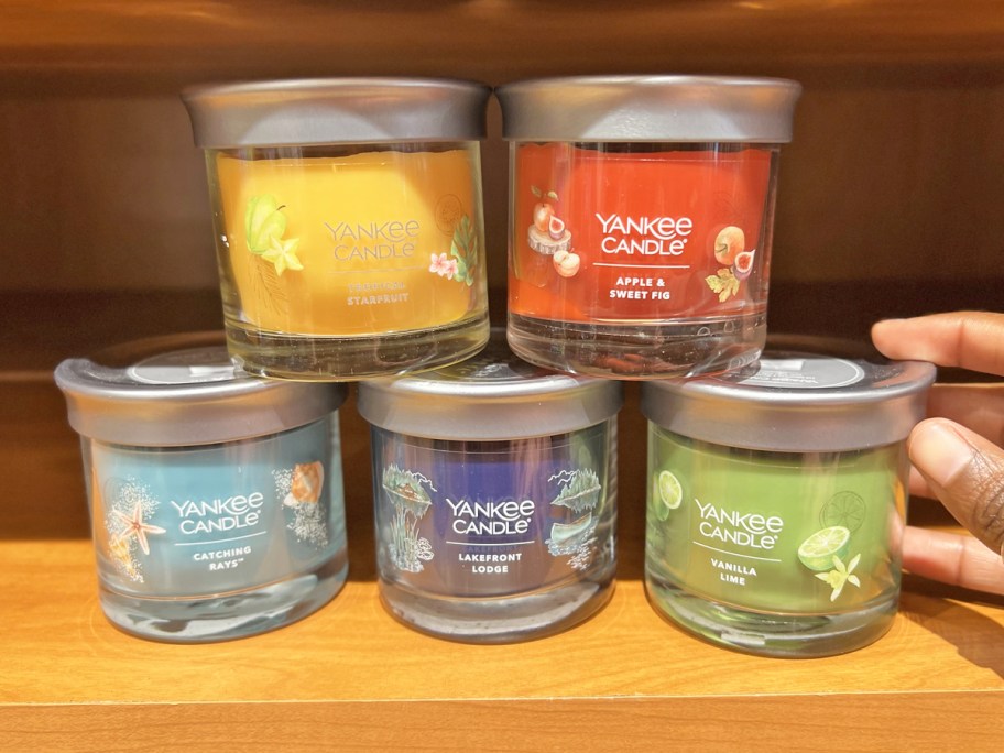 hand touching a stack of Yankee Candle Signature Small Jar Candles