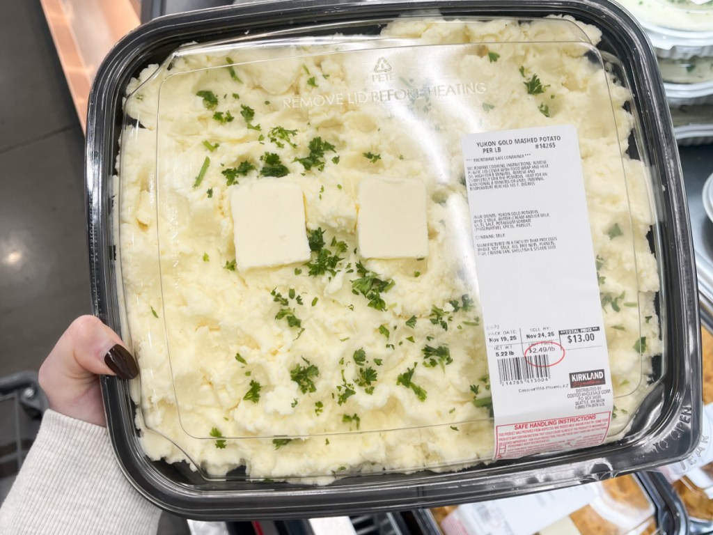 Woman holding container of Yukon gold mashed potatoes inside Costco
