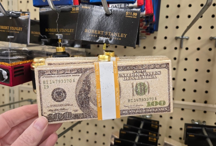 a womans hand holding a stack of 100 bills as an ornament