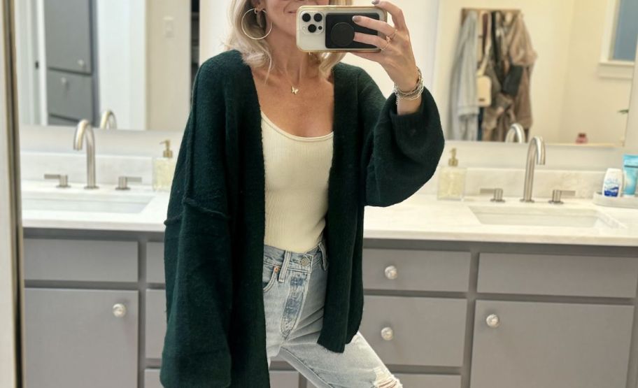 a woman in a green sweater taking a selfie