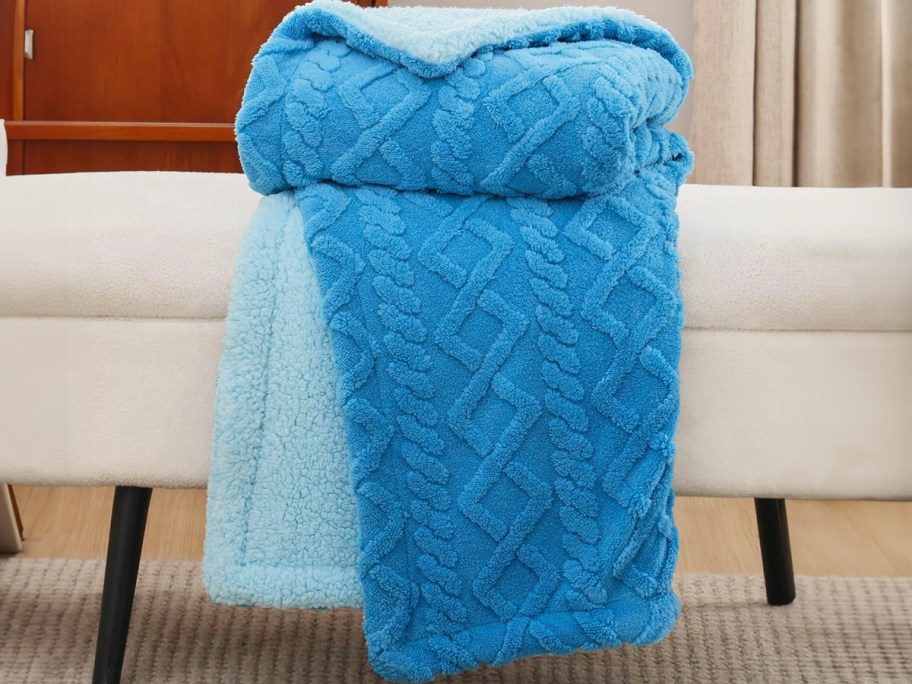 blue throw blanket folded on top of white bench 