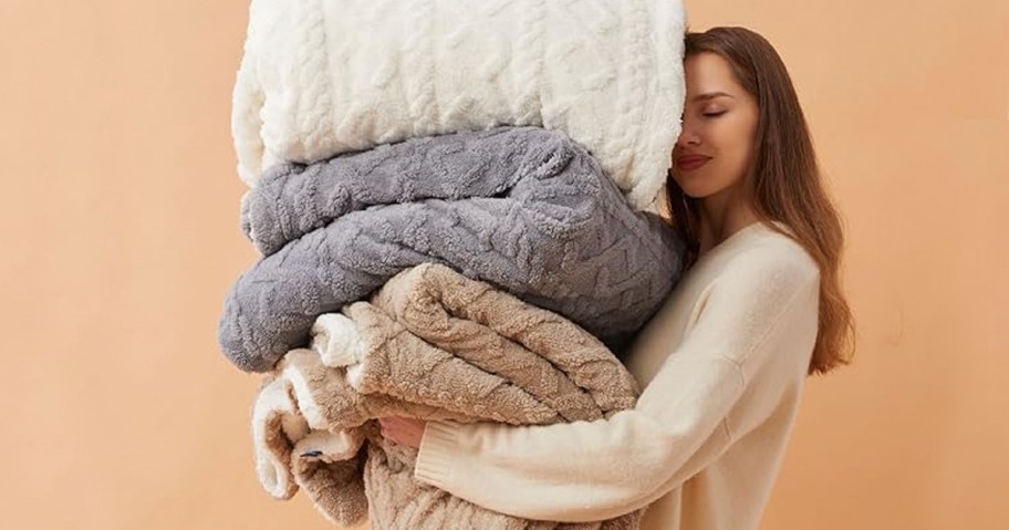 woman holding white, gray and brown blankets 