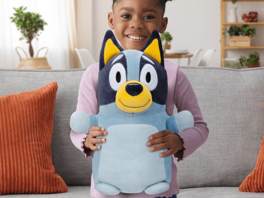 young girl holding a bluey squishmallow on her lap