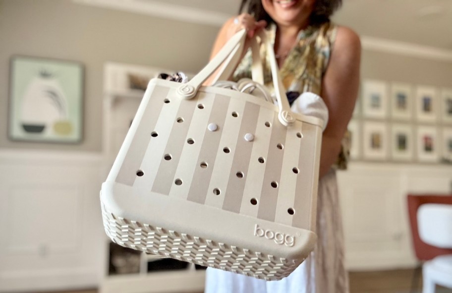 woman holding up striped bogg bag