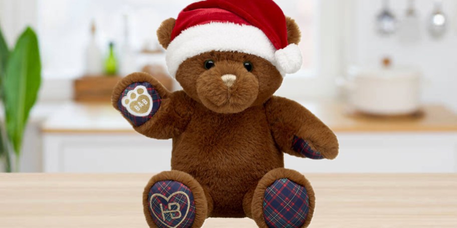 brown teddy bear with red santa hat on countertop