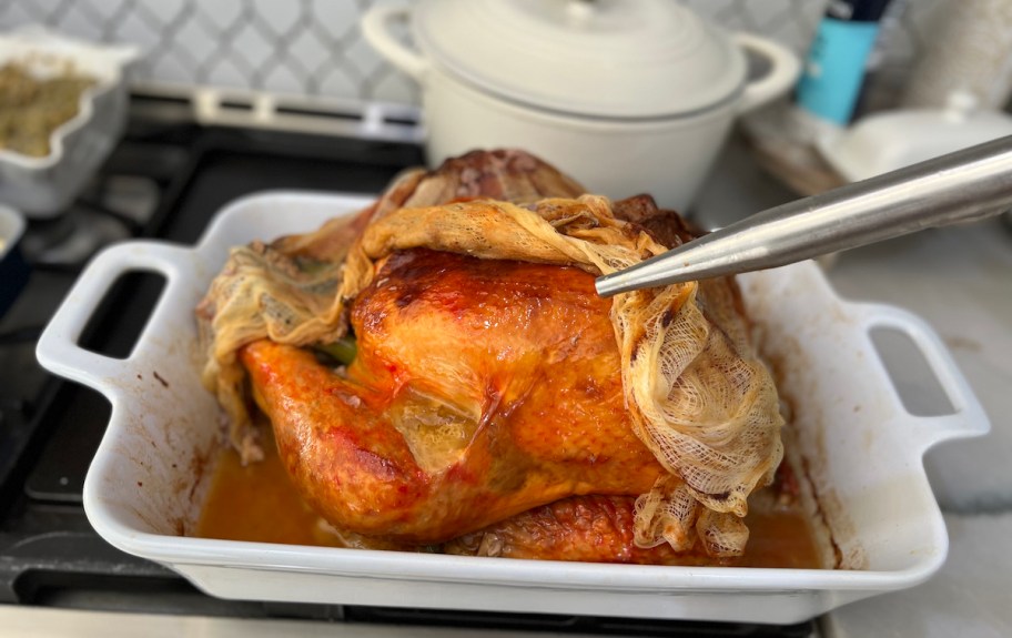 crispy whole turkey in white casserole dish on top of stovetop