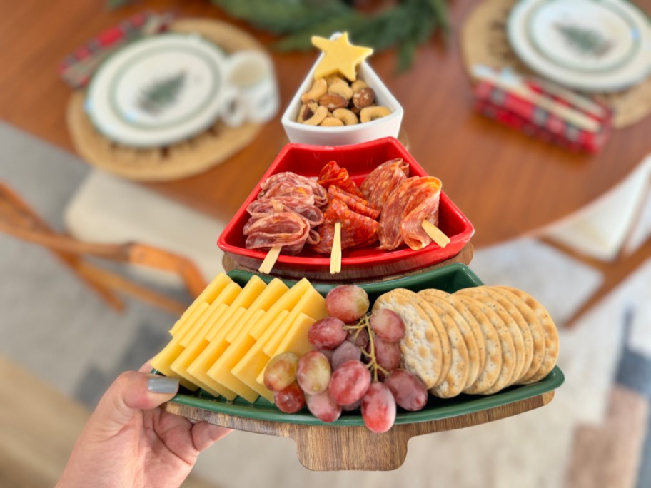 hand holding a christmas tree charcuterie tray filled with food