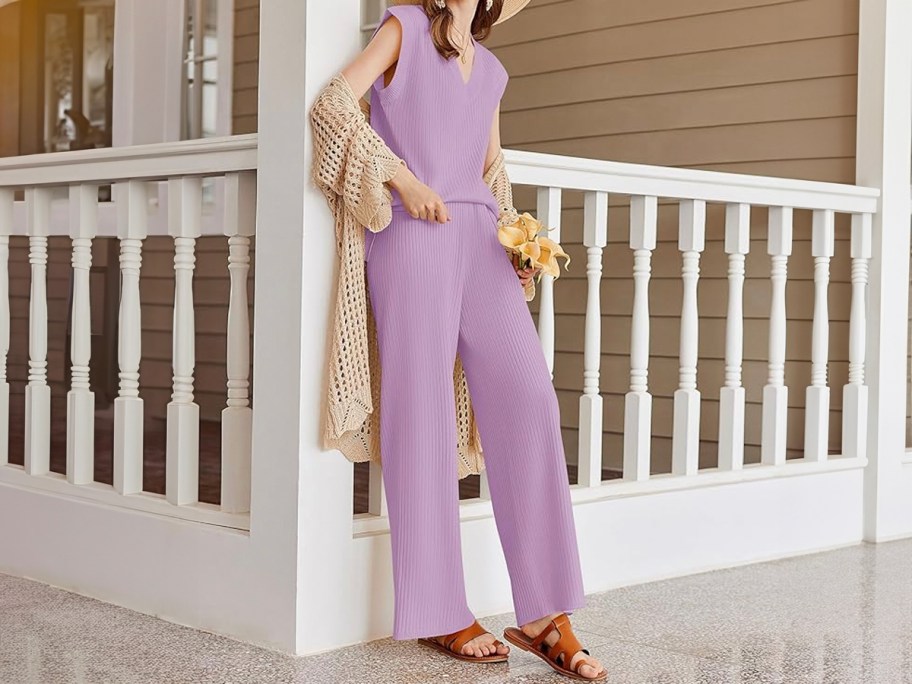 woman wearing purple lounge set leaning against fence 