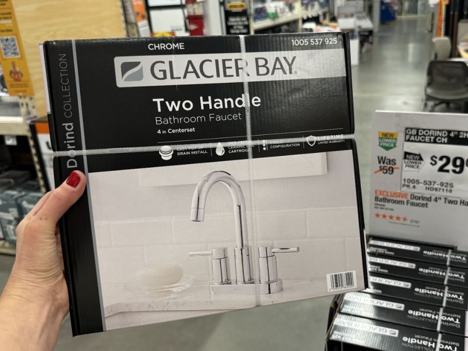 a womans hand holding a bathroom faucet box