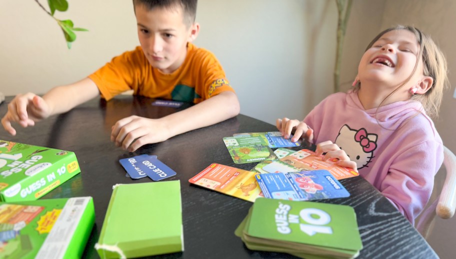 two kids sitting at table playing guess in 10 board game