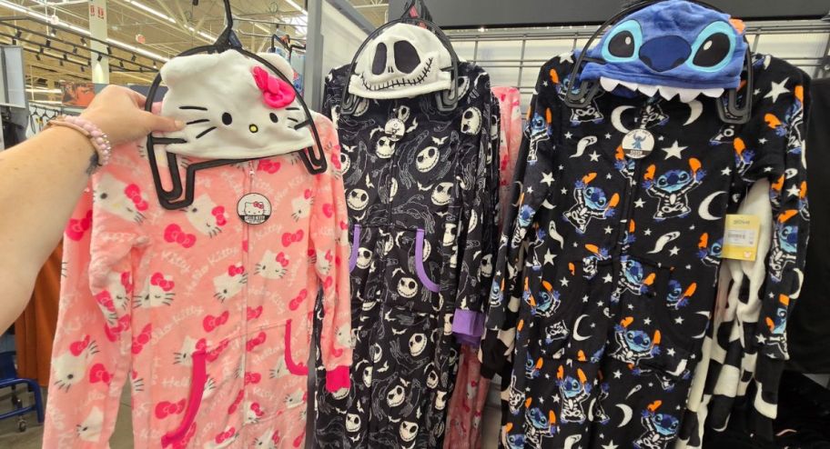 hand holding three halloween suit pjs from walmart