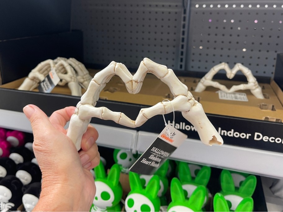 womans hand holding a pair of skeleton hands make the heart sign