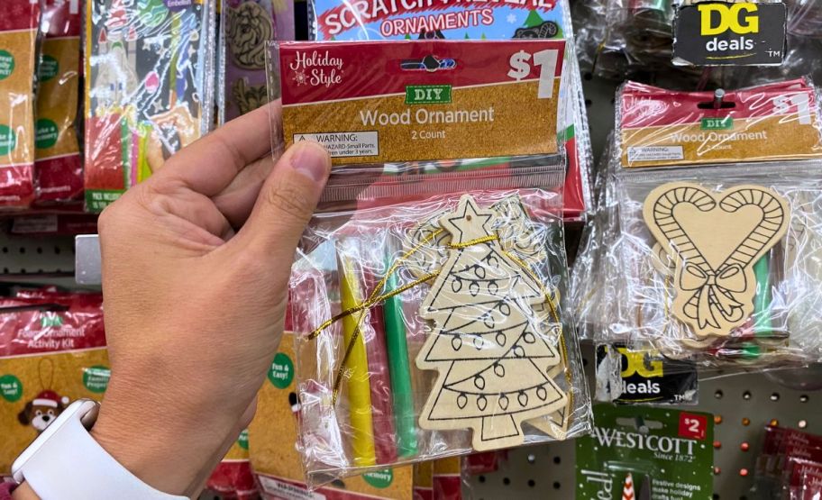 a womans hand holding a packaged holiday ornament craft