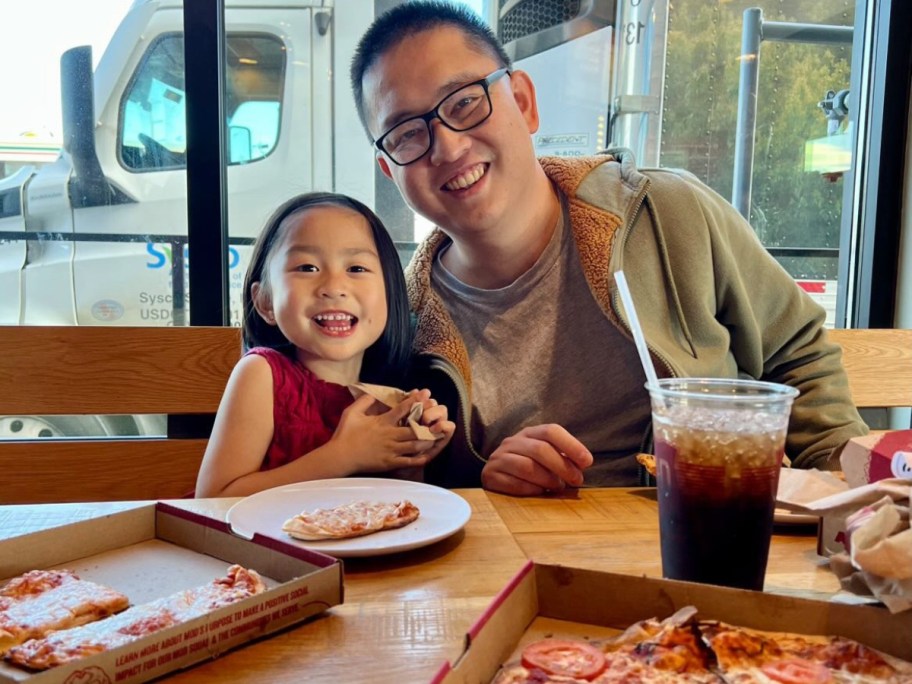 girl eating pizza with man wearing glasses