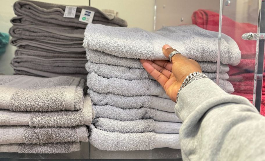 a woman's hand grabbing a big one towel from a store display