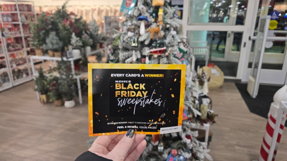 hand holding up a kohls black friday mystery sweepstakes coupon in store