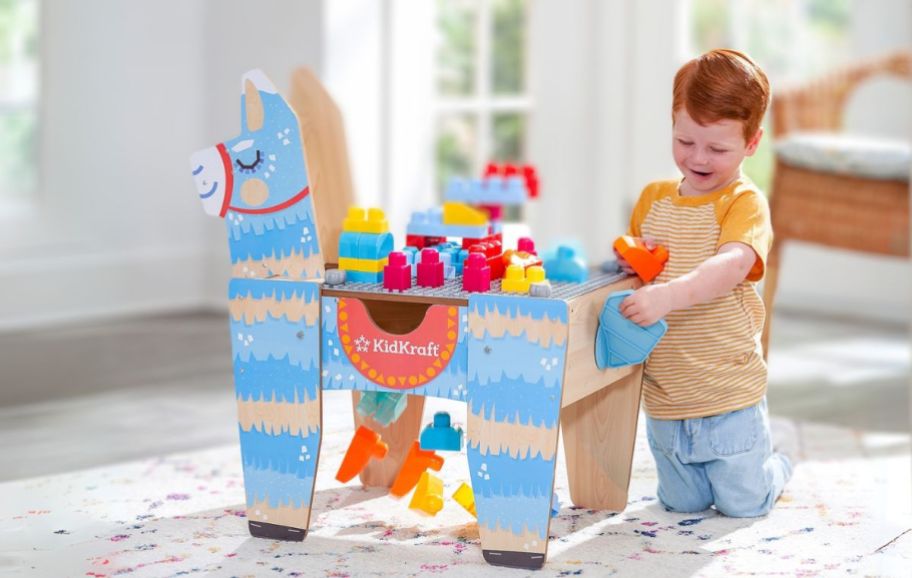 a little boy playing on a building blocks table