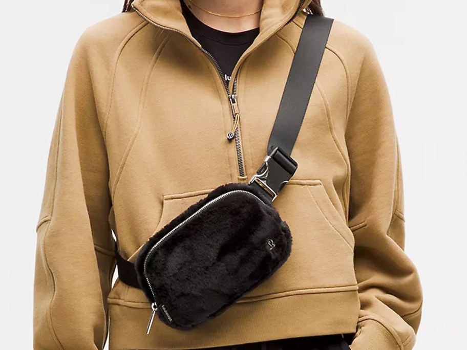 woman in brown sweatshirt with a black fleece belt bag across chest