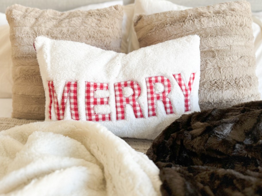 merry sherpa throw pillow on bed