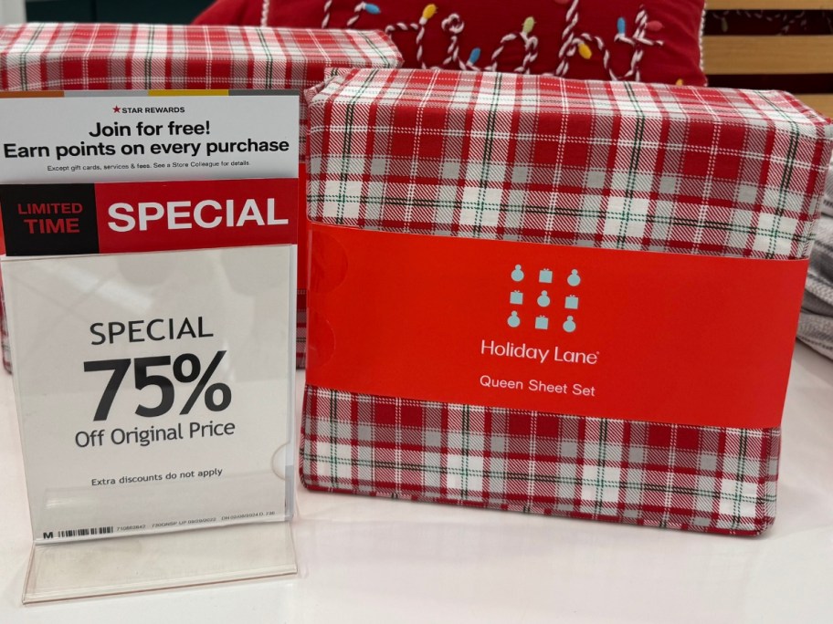 sets of red plaid Christmas bed sheets on a store display with a sign that says 75% off