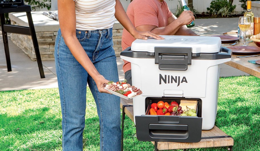 woman holding food next to a white ninja cooler