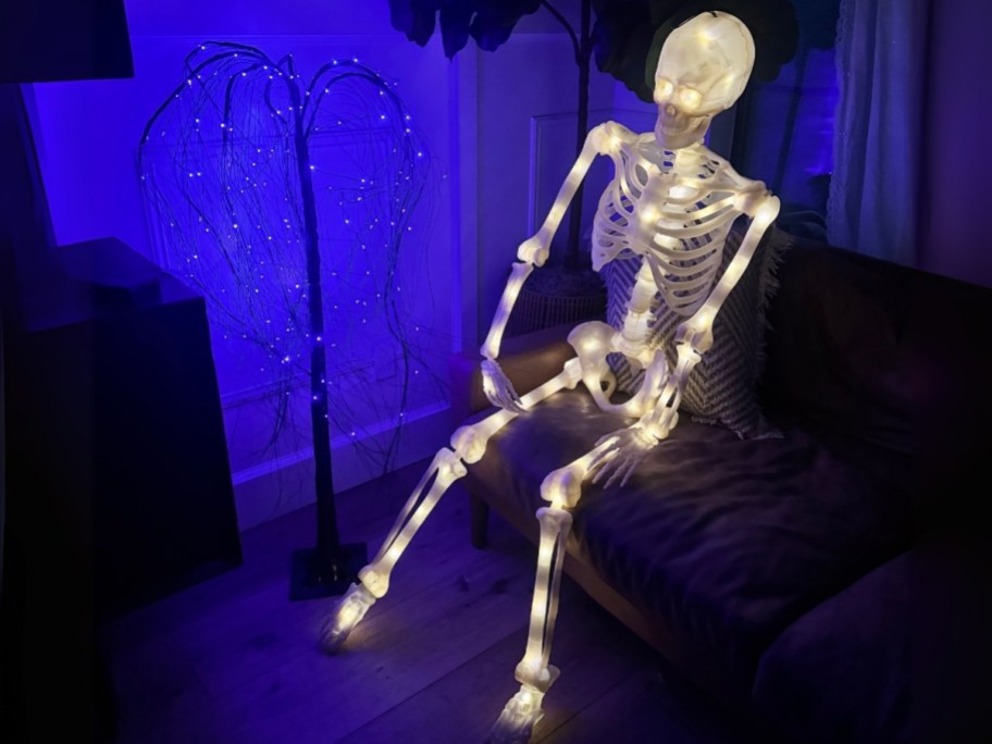 led posable skeleton sitting on a sofa with LEDs on