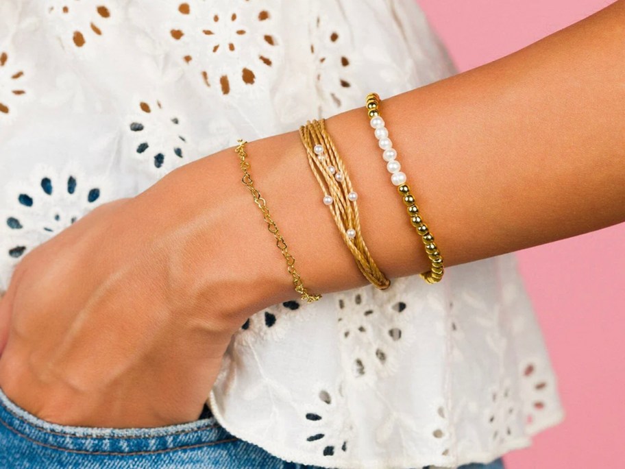 person wearing gold and pearl bracelets 