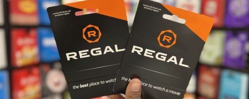 a womans hand holding 2 regal cinema gift cards