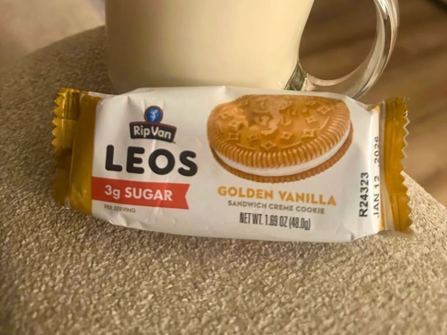 Rip Van LEOs Golden Vanilla Sandwich Cookie pack leaning against a mug of milk