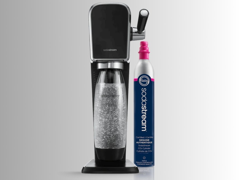 a black SodaStream Art Machine with a bottle inside with carbonated drink and a CO2 Cylinder next to it