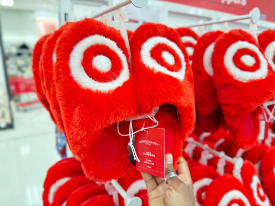 hand holding the bottom of a pair of bullseye logo slippers at target