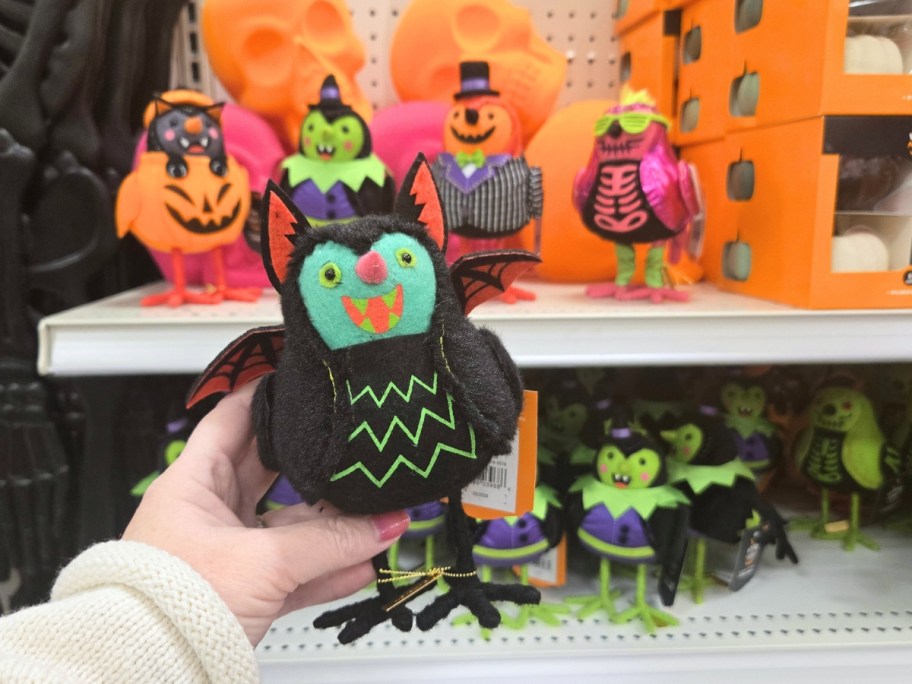 hand holding a small decorative bird dressed as Dracula