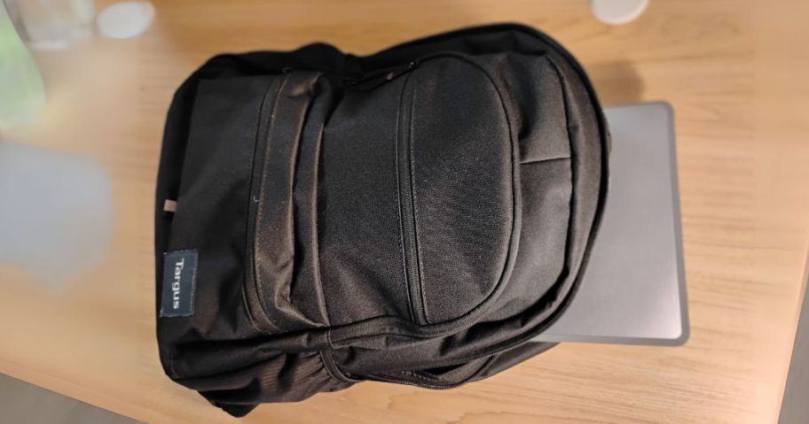 black targus laptop backack on desk with laptop sticking out