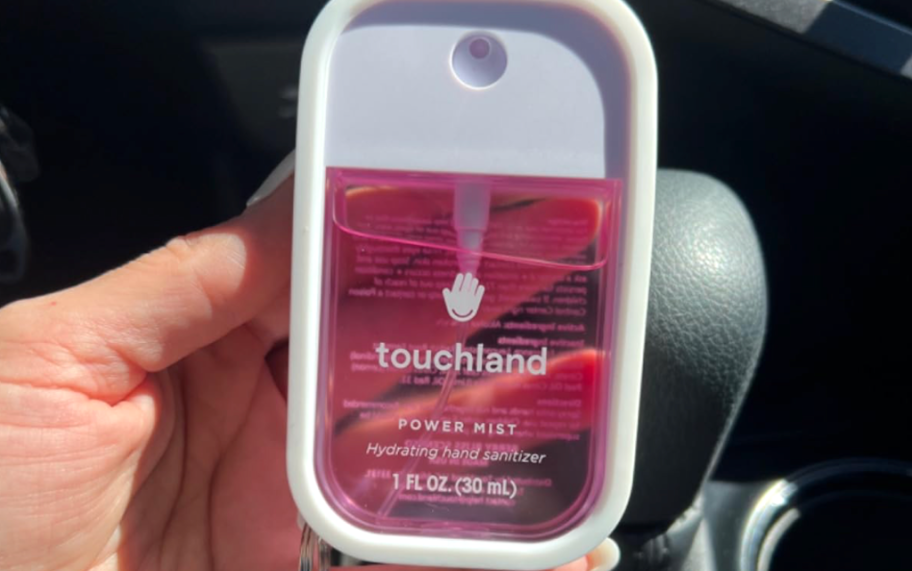 holding a pink Touchland hand sanitizer in a white case