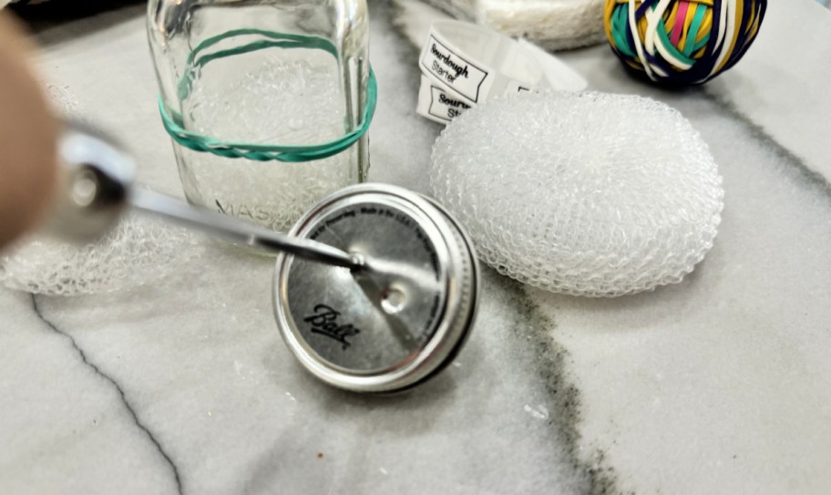 using an ice pick to poke holes in jar lid