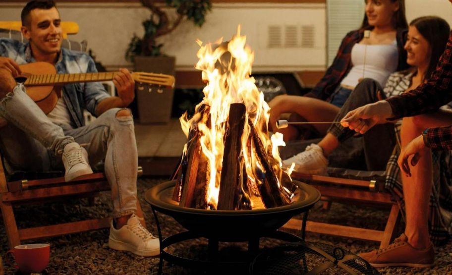 4 people gathered around a firepit as they camp out in an RV