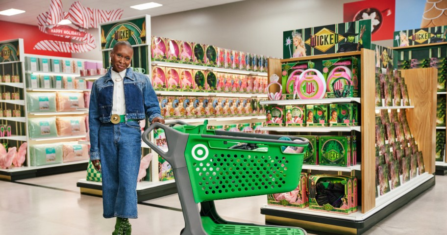 woman posing next to a green target shopping cart in-store